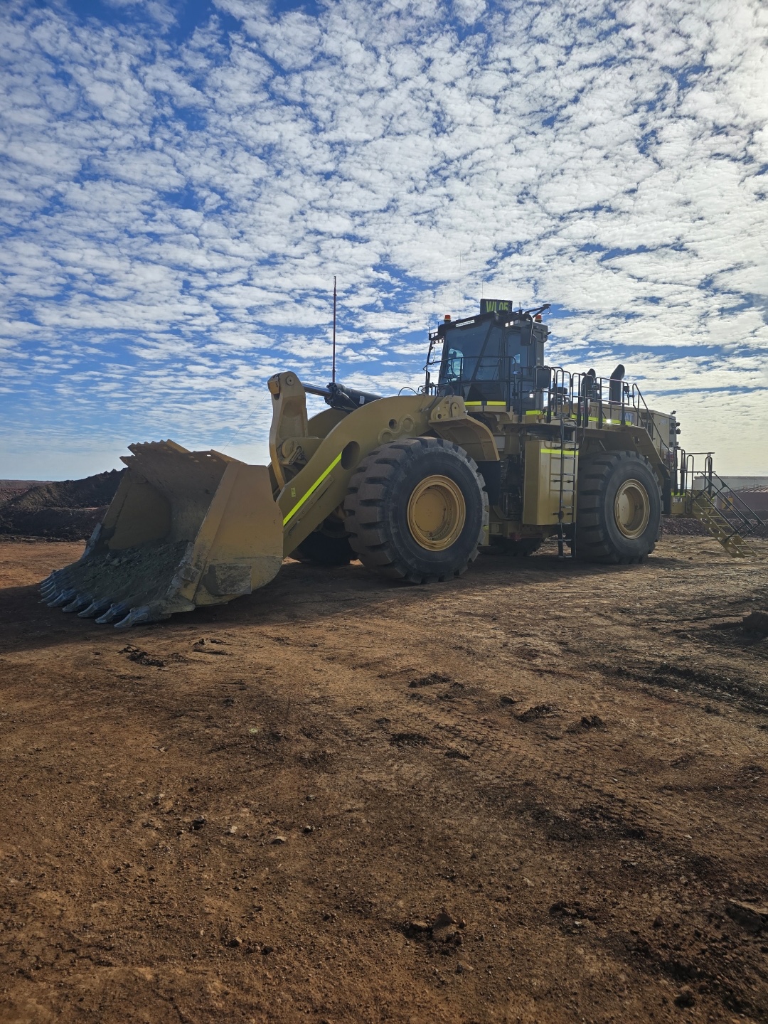 A CAT large wheel loader, fleet number WL05, parked on a mine pad under a mackerel sky.