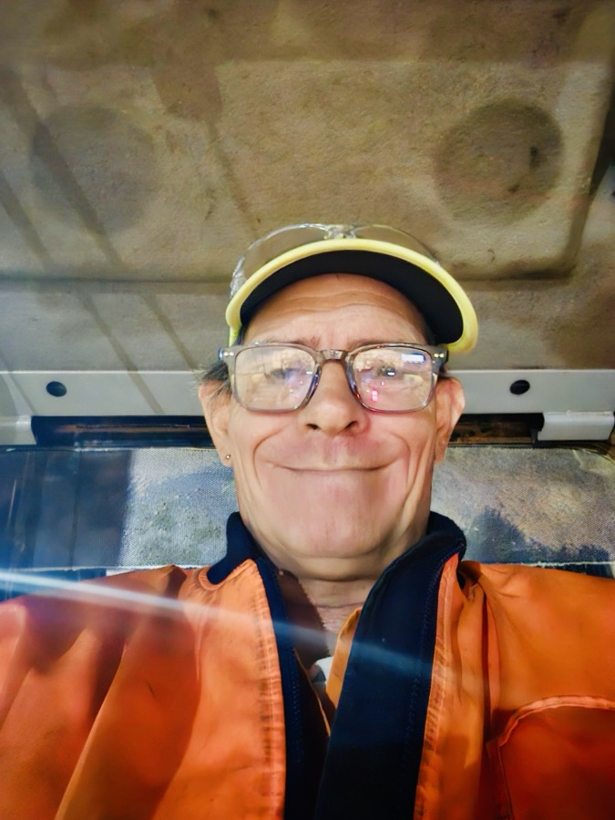 Neil Hughes in hi-vis and a hard hat, sitting in a machine cab.